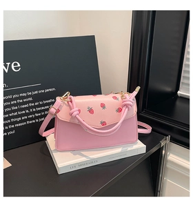 Pink faux leather crossbody bag with red strawberry print and elegant knotted handle detail