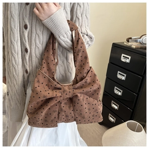 Bruine corduroy hobo-tas met grote strik en hartpatronen, gedragen over de schouder