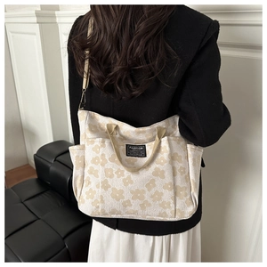 Detail of floral canvas tote bag with side pocket and comfortable strap shown on model