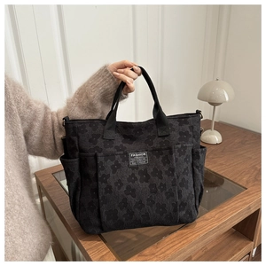 Close-up of black floral jacquard texture and Fashion Instinct label on large tote bag