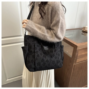 Detailed macro view of black 3D flower jacquard texture and fashion label on the tote bag
