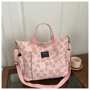 Detail of pink floral canvas tote bag featuring front pocket and adjustable shoulder strap