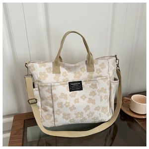 Detail of canvas tote bag with floral print, shoulder strap and fashion instinct label