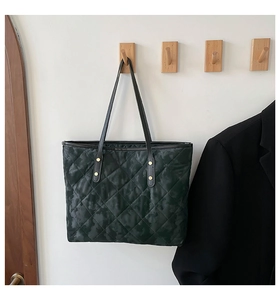 Detail of green quilted tote bag showing rhombus stitching and golden metal rivets
