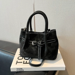 Minimalist black suede tote bag with white stitching and decorative leather straps