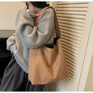 Dettaglio della borsa tote in tela marrone con ampia tracolla indossata da una modella