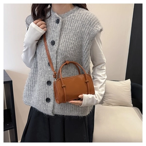 Brown leather crossbody bag detail on model with top handles and fashion text