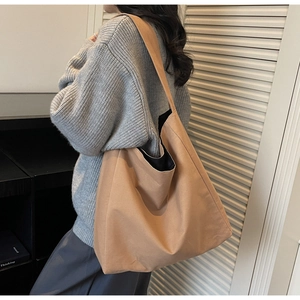 Model wearing a large minimalist canvas tote bag in brown with casual slouchy design