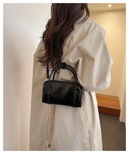 Fashionable black glossy crossbody box bag styled on a beige trench coat for women