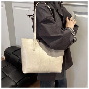 Detail view of the elegant beige leather texture and stitching on the tote bag