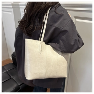 Close-up of the asymmetrical curved edge and textured leather on this beige tote bag