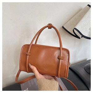 Close-up of brown textured leather square handbag with Fashion logo in home setting