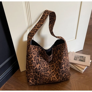 Dettaglio della borsa tote in tela leopardata con tracolla larga su sfondo minimal