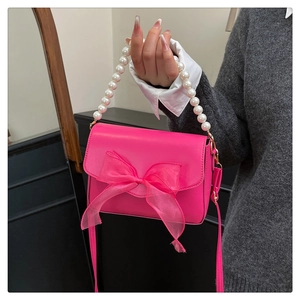 Close-up of fuchsia leather handbag with organza bow and pearl handle detail