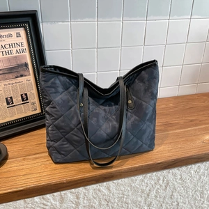 Deep grey quilted tote bag with diamond pattern and black leather shoulder straps