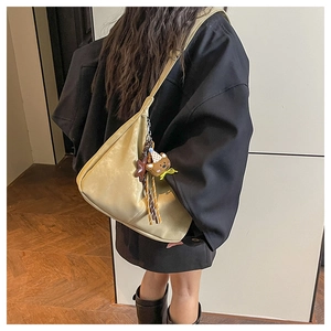 Vue détaillée du grand sac beige avec pendentif ours et pompon décoratif