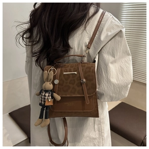 Detail of a brown leather backpack with leopard print flap and a cute rabbit charm