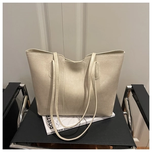 Detail of a minimalist cream-colored tote bag with fine leather texture on a stylish chair
