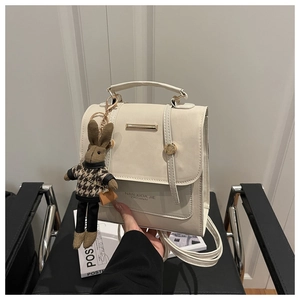 Detail of cream white leather backpack with metal bar and cute rabbit doll charm