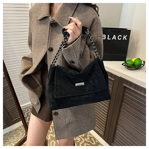 Detail of matte black suede texture on crossbody bag with braided silver chain strap