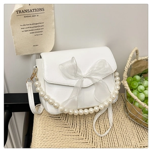 Detailed shot of white leather handbag with large organza bow and pearl shoulder strap