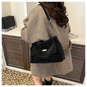 Detail showing the textured black crossbody bag with silver buckle and chain strap