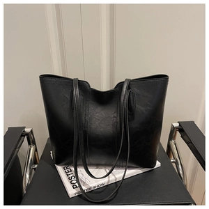 Detail of a black textured leather tote bag showing a large capacity and shoulder straps
