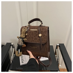 Detail view of leopard print flap and brown leather bag with a cute rabbit keychain charm