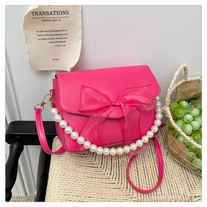 Detailed view of rose pink handbag with large organza bow and pearl handle strap