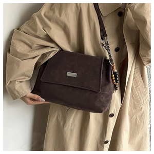 Detail of dark brown vintage crossbody bag with wood bead chain and textured finish