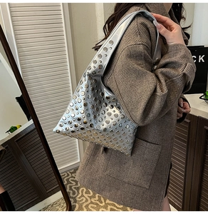 Detailed shot of silver rivet studded hobo bag with metallic finish on model shoulder