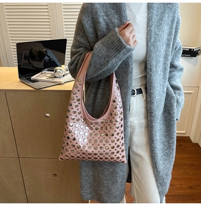 Close-up of pink leather hobo bag featuring decorative silver metal rivets and hobo handle