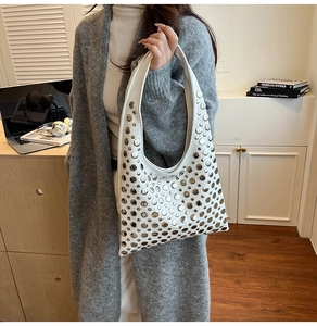 Close-up of white leather hobo bag with silver rivet studs worn by a model