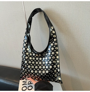 Close-up of black PU leather shoulder bag with decorative silver round rivets and hobo style