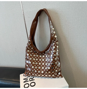 Detail of brown glossy hobo bag with silver metallic rivets on a minimalist display
