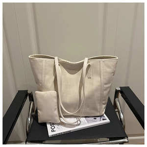 Sac fourre-tout crème minimaliste avec petite pochette zippée sur une chaise en cuir