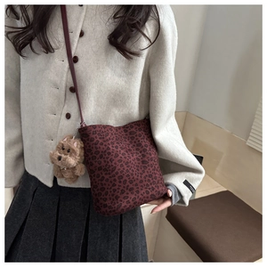 Detail of dark red leopard print bucket bag with a cute plush puppy charm accessory