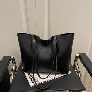Minimalist black leather tote bag with long straps on a magazine for a stylish commute