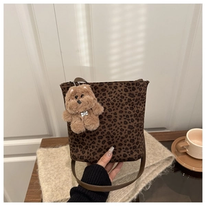 Detail of leopard print bucket bag with plush dog charm in an autumn lifestyle setting