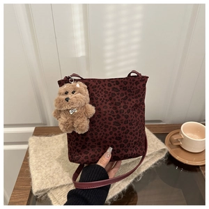 Close-up of leopard print bucket bag with plush bear charm on a cozy tabletop