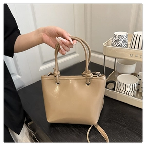 Detail of khaki faux leather shoulder bag with decorative knot handle and crossbody strap