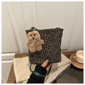 Detail of leopard print canvas bucket bag with green handle and plush dog charm