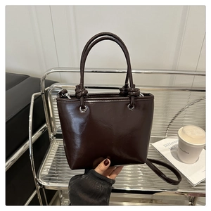 Macro shot of dark brown glossy leather handbag with knotted handle and fine stitching