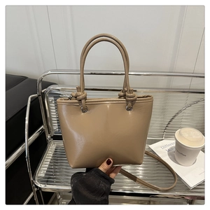 Close-up of khaki shoulder bag featuring unique knot detail on strap and smooth leather texture