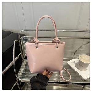 Detailed view of a pink PU leather bucket bag with knot handle and adjustable strap