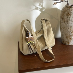 Minimalist beige tote bag with cute bear charm and adjustable strap on wooden table