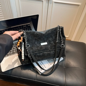 Vintage black chain crossbody bag with silver hardware and bead tassel on leather seat