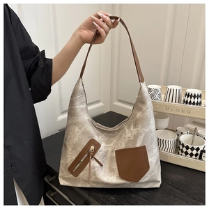 Detailed side view of canvas tote bag with brown leather accents shown on a model