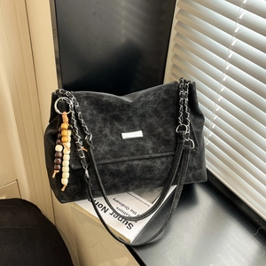Retro black leather shoulder bag with chain strap and bead charm on a window sill
