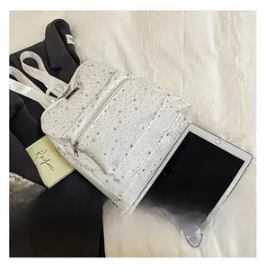 Close-up of white backpack with silver star patterns, front zipper pocket and carry handle